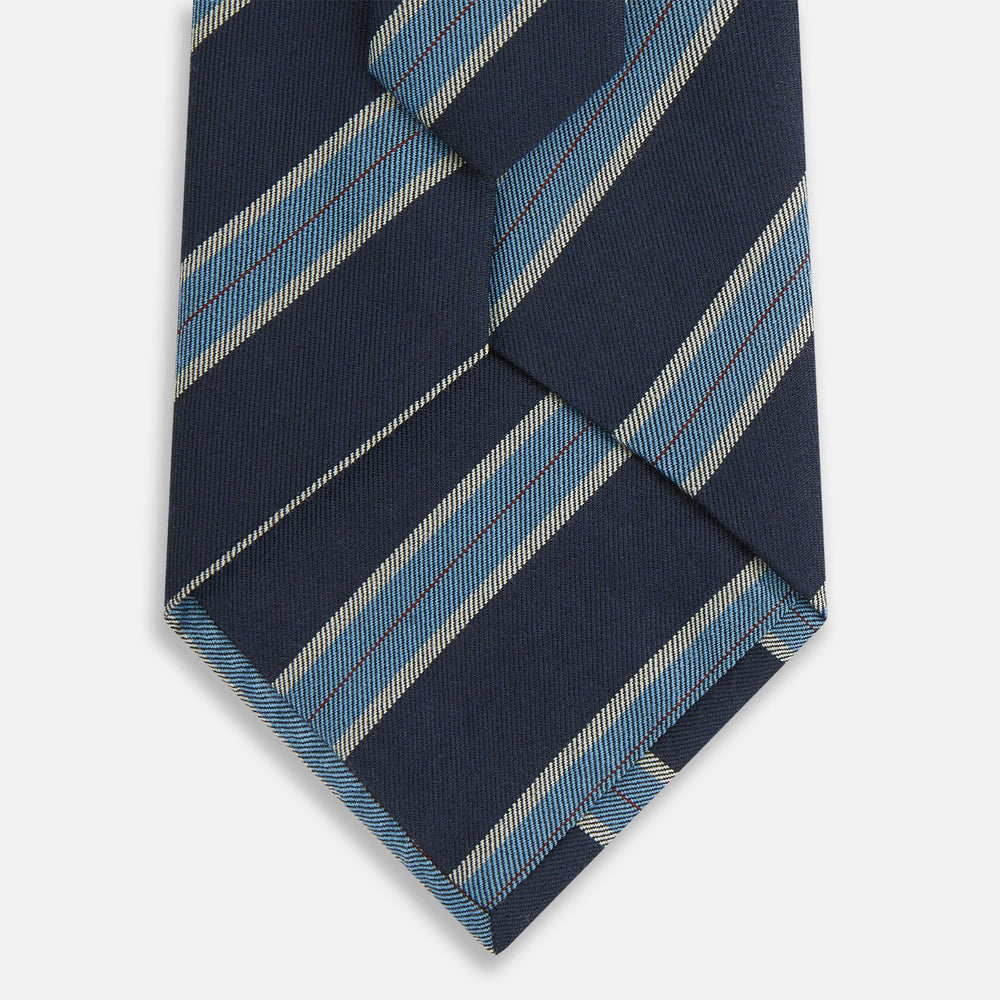 The Turnbull & Asser Blue Multi Stripe Silk Blend Tie features navy, light blue, and silver diagonal stripes and is displayed rolled up on a white background. An ideal pairing with Turnbull & Asser shirts.