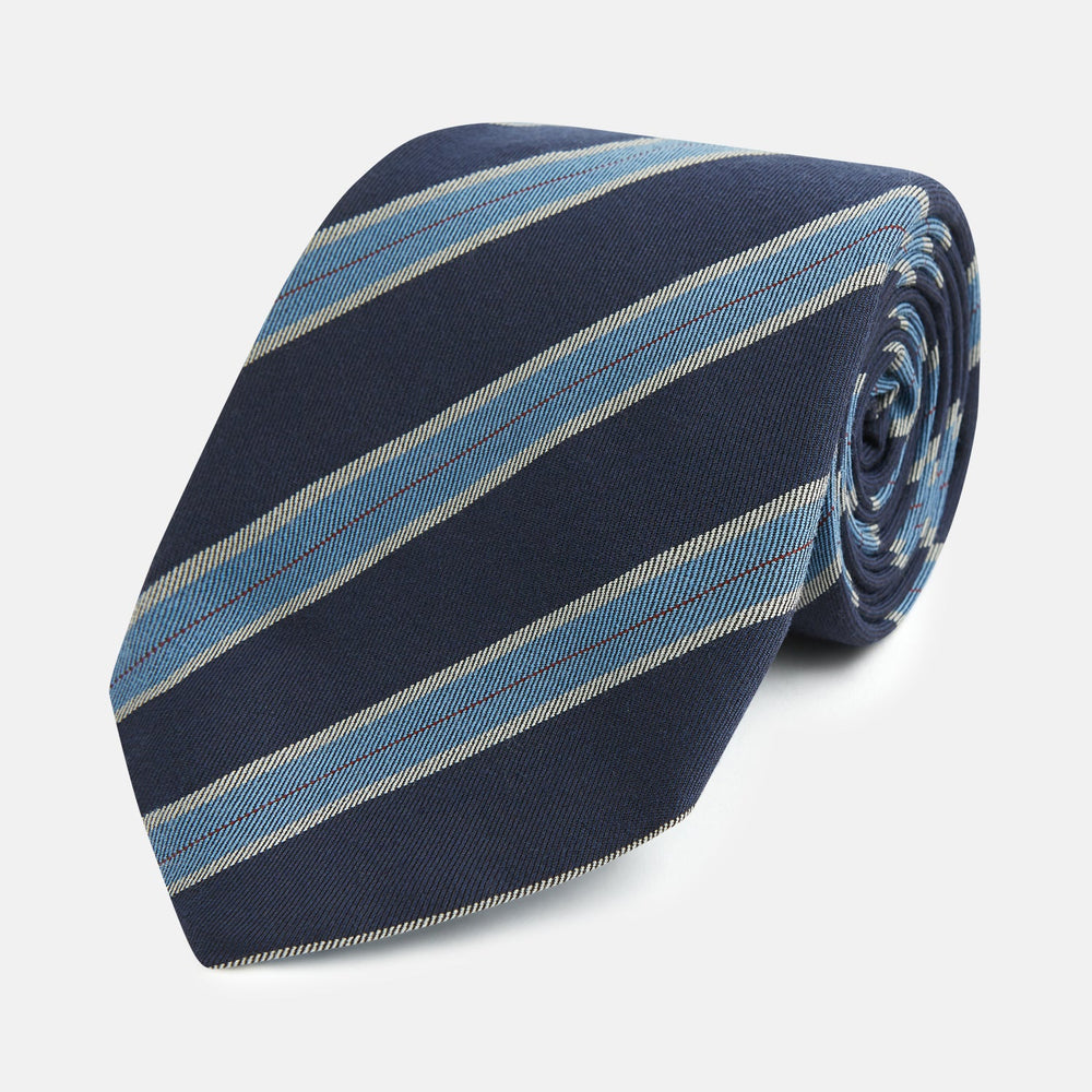 The Turnbull & Asser Blue Multi Stripe Silk Blend Tie features navy, light blue, and silver diagonal stripes and is displayed rolled up on a white background. An ideal pairing with Turnbull & Asser shirts.