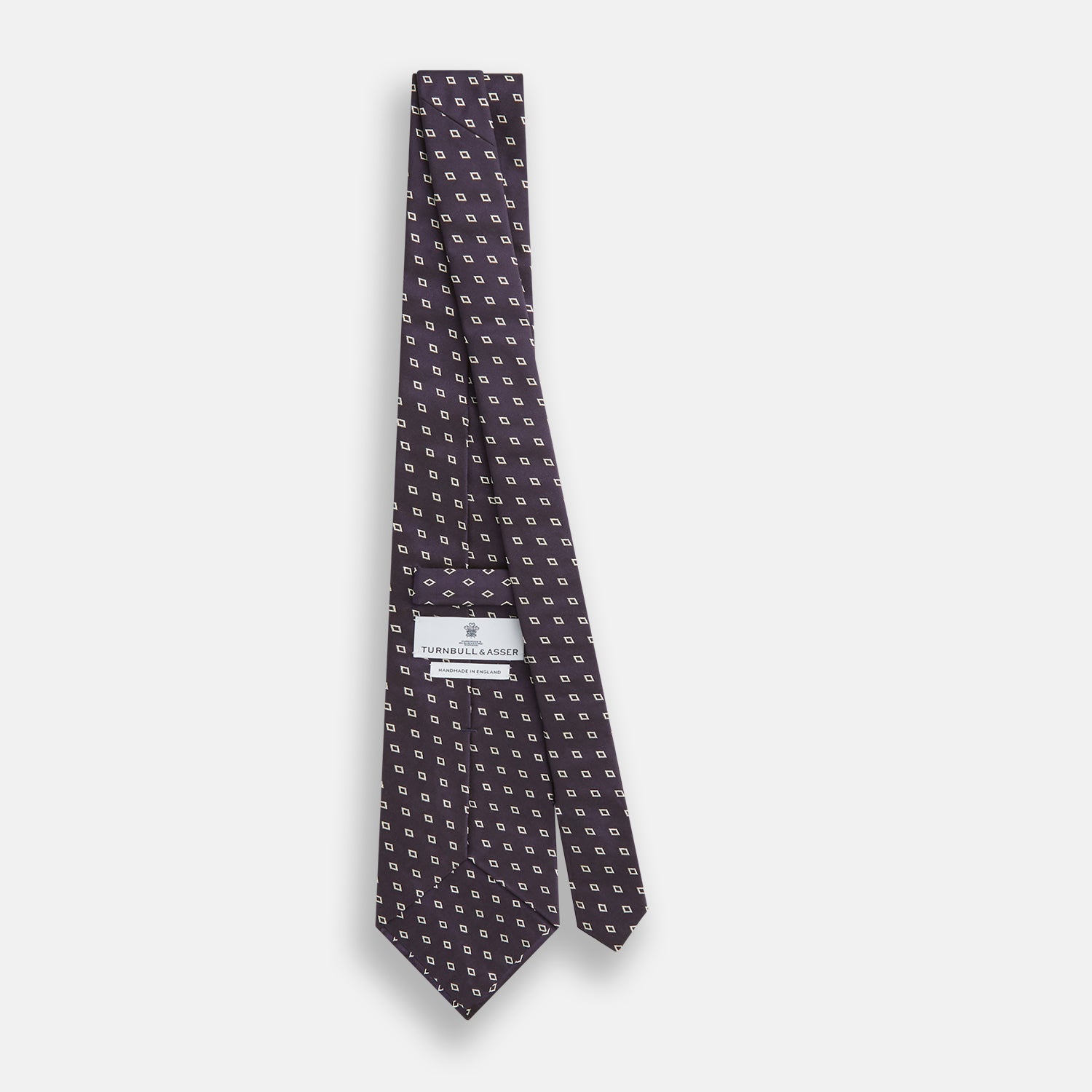 View 4 of product The Blue Diamond Silk Tie by Turnbull & Asser, featuring a blue micro diamond pattern, is rolled up and displayed on a white background. Perfect to complement Turnbull & Asser shirts.