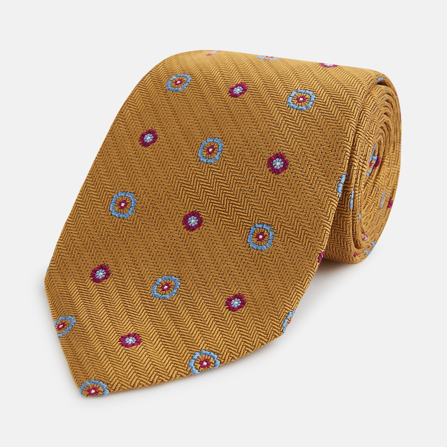 View 1 of product The Gold Motif Silk Tie by Turnbull & Asser features a refined yellow herringbone texture with blue and red floral accents, capturing British elegance—a sophisticated addition to any discriminating wardrobe.