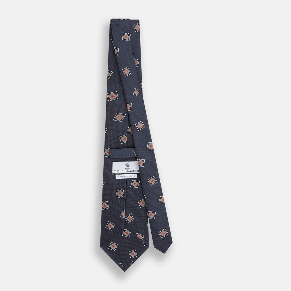 The Turnbull & Asser Grey Square Overlay Silk Tie features a refined chevron pattern with gray square motifs and subtle red accents, expertly handmade for formal occasions. Presented neatly rolled on a white background.