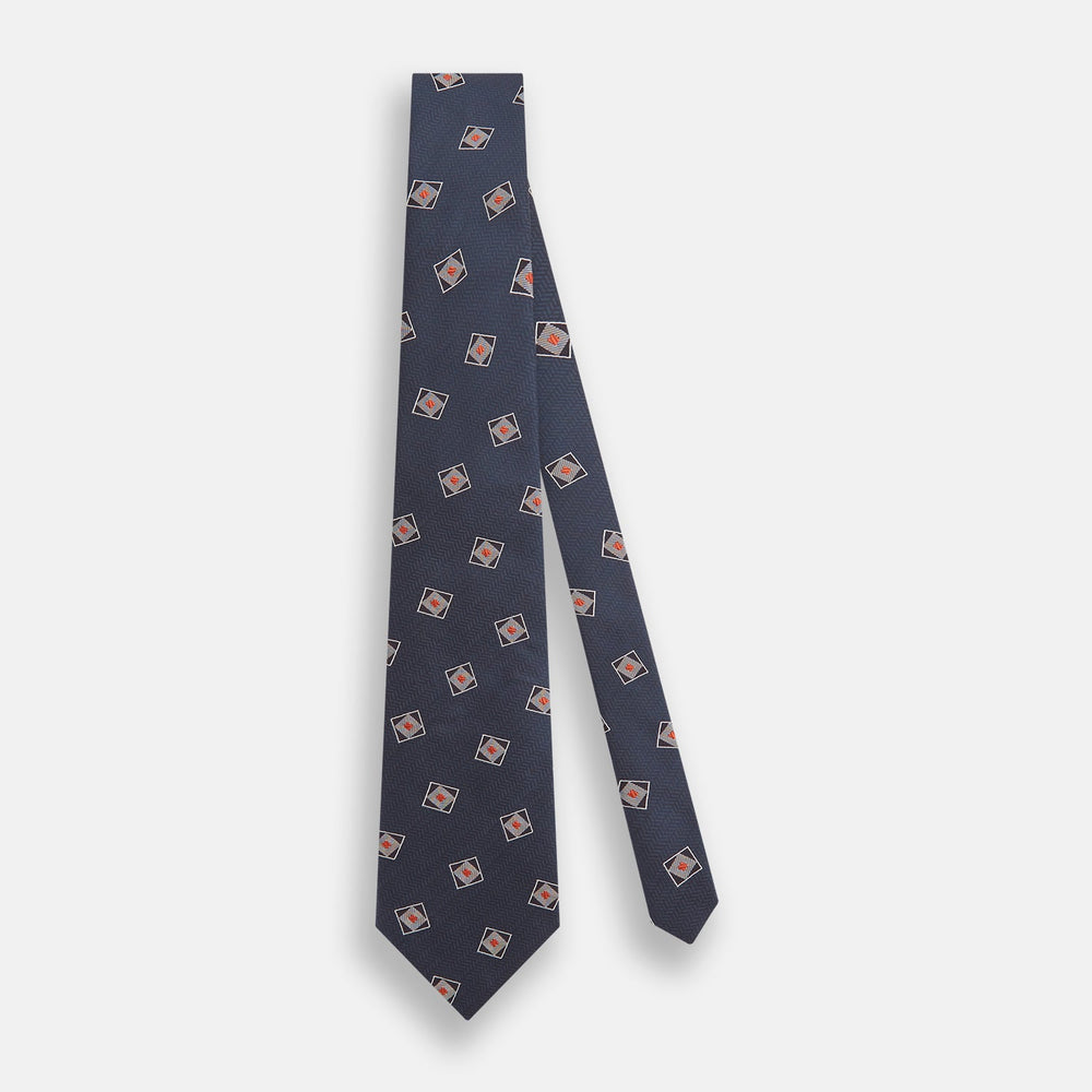 The Turnbull & Asser Grey Square Overlay Silk Tie features a refined chevron pattern with gray square motifs and subtle red accents, expertly handmade for formal occasions. Presented neatly rolled on a white background.