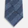 View 3 of product The Turnbull & Asser Blue Block Stripe Silk Tie, featuring a refined striped pattern, is elegantly showcased rolled up against a plain white background.