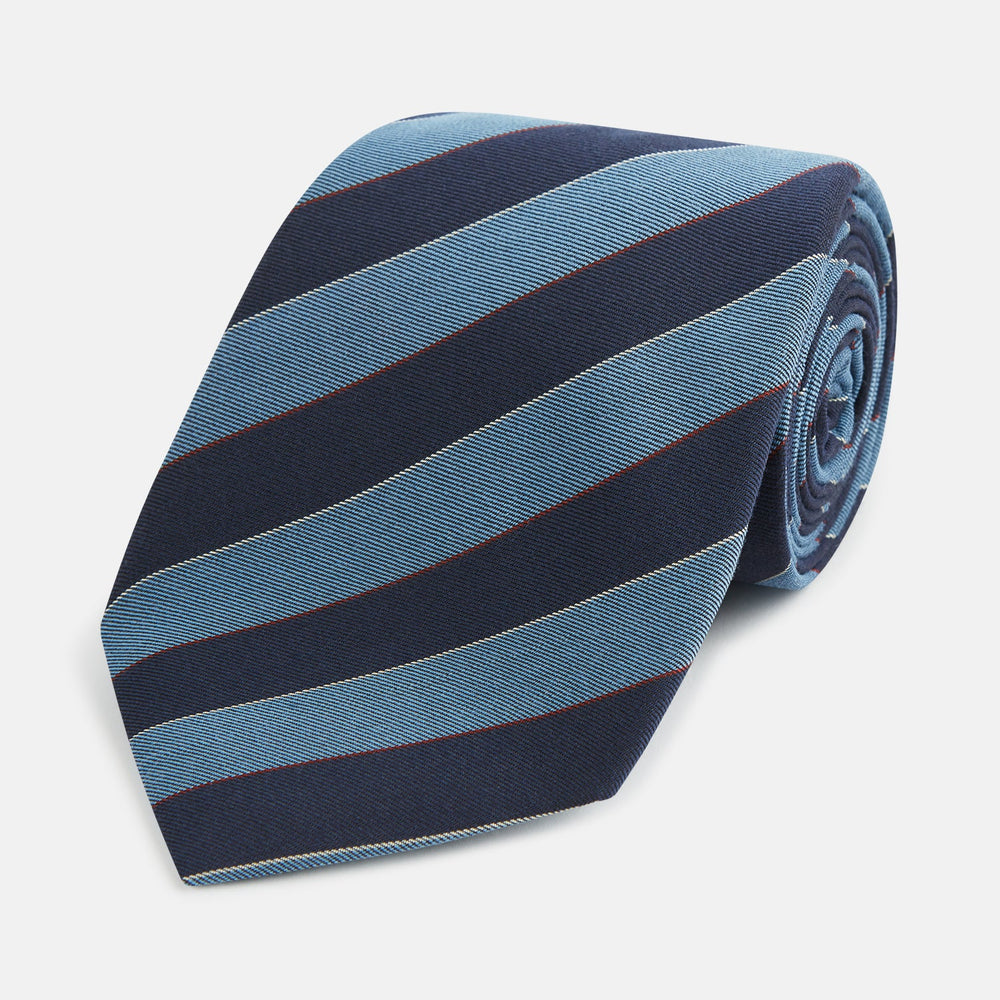 The Blue Block Stripe Silk Blend Tie by Turnbull & Asser features light blue and navy diagonal stripes with thin red lines—a stylish accessory that pairs perfectly with Turnbull & Asser shirts. Displayed rolled-up on a white background.