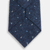 View 3 of product The Turnbull & Asser Navy Micro Paisley Silk Tie features a rolled-up navy blue silk with a subtle speckled texture and small light blue paisley patterns, perfect for enhancing any formal collection, shown on a white background.