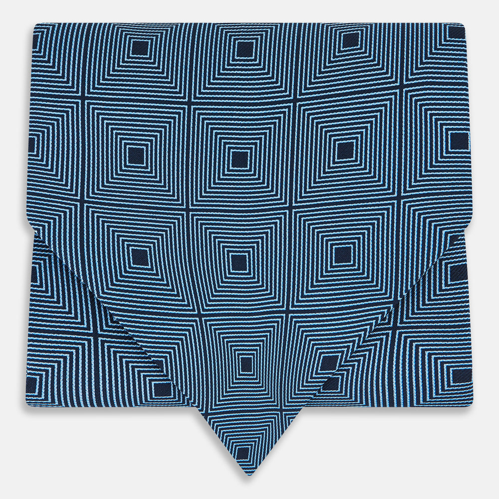 The Blue and Navy Concentric Square Printed Silk Cravat from Turnbull & Asser UK features a geometric blue and white design on a dark background, creating an optical illusion—an elegant wedding accessory.