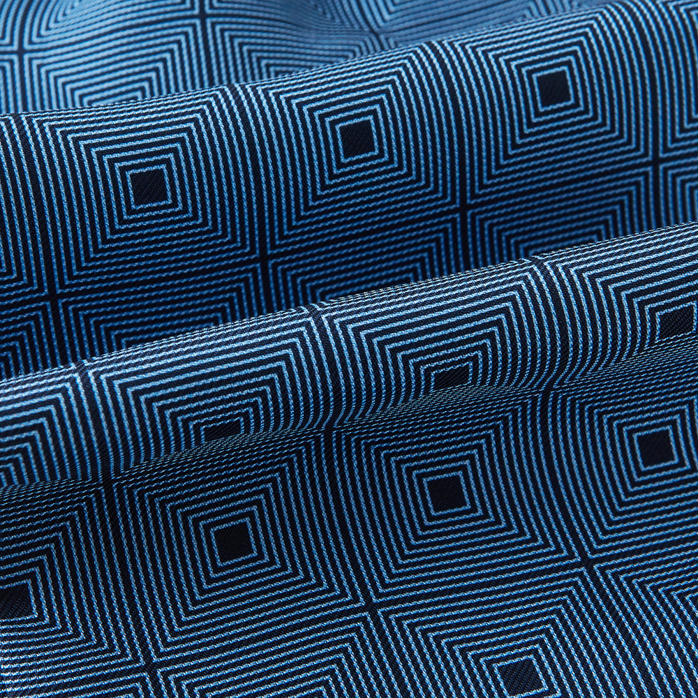 The Blue and Navy Concentric Square Printed Silk Cravat from Turnbull & Asser UK features a geometric blue and white design on a dark background, creating an optical illusion—an elegant wedding accessory.