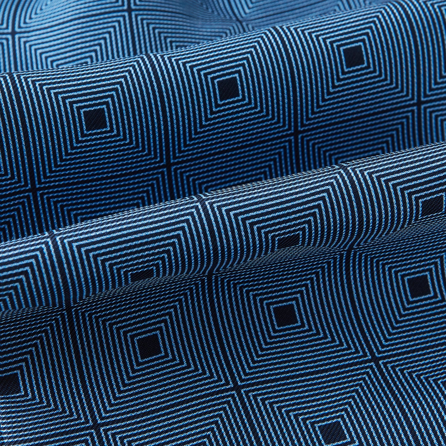View 4 of product The Blue and Navy Concentric Square Printed Silk Cravat from Turnbull & Asser UK features a geometric blue and white design on a dark background, creating an optical illusion—an elegant wedding accessory.