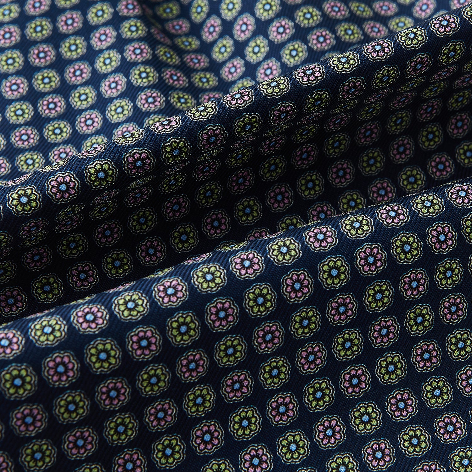 View 4 of product Close-up of the Turnbull & Asser UK Dark Navy Contrasting Rosette Medallion Printed Silk Cravat, featuring folded dark blue silk with a vibrant pattern of pink, yellow, and green rosette medallions.
