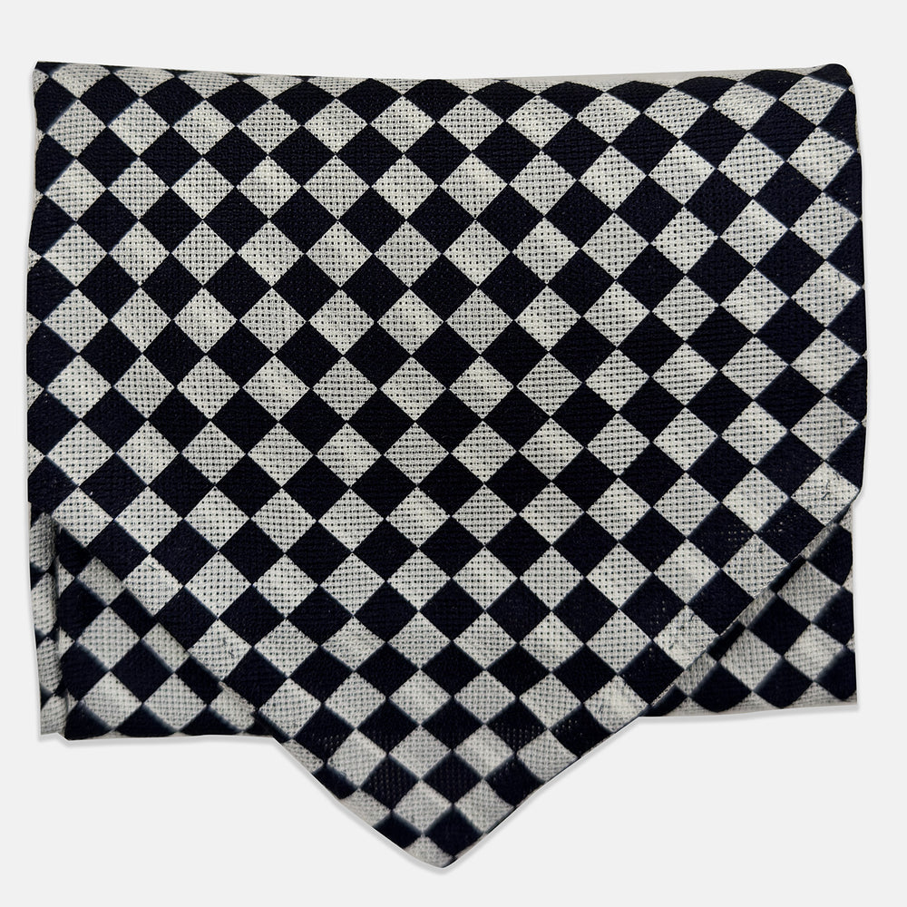 A folded Chequered Navy & White Silk Cravat by Turnbull & Asser UK, featuring a timeless diamond checkered pattern that channels classic British motoring elegance, displayed on a plain white background. Ideal as a double-sided silk accessory to elevate your ensemble for the Concours of Elegance 2026.