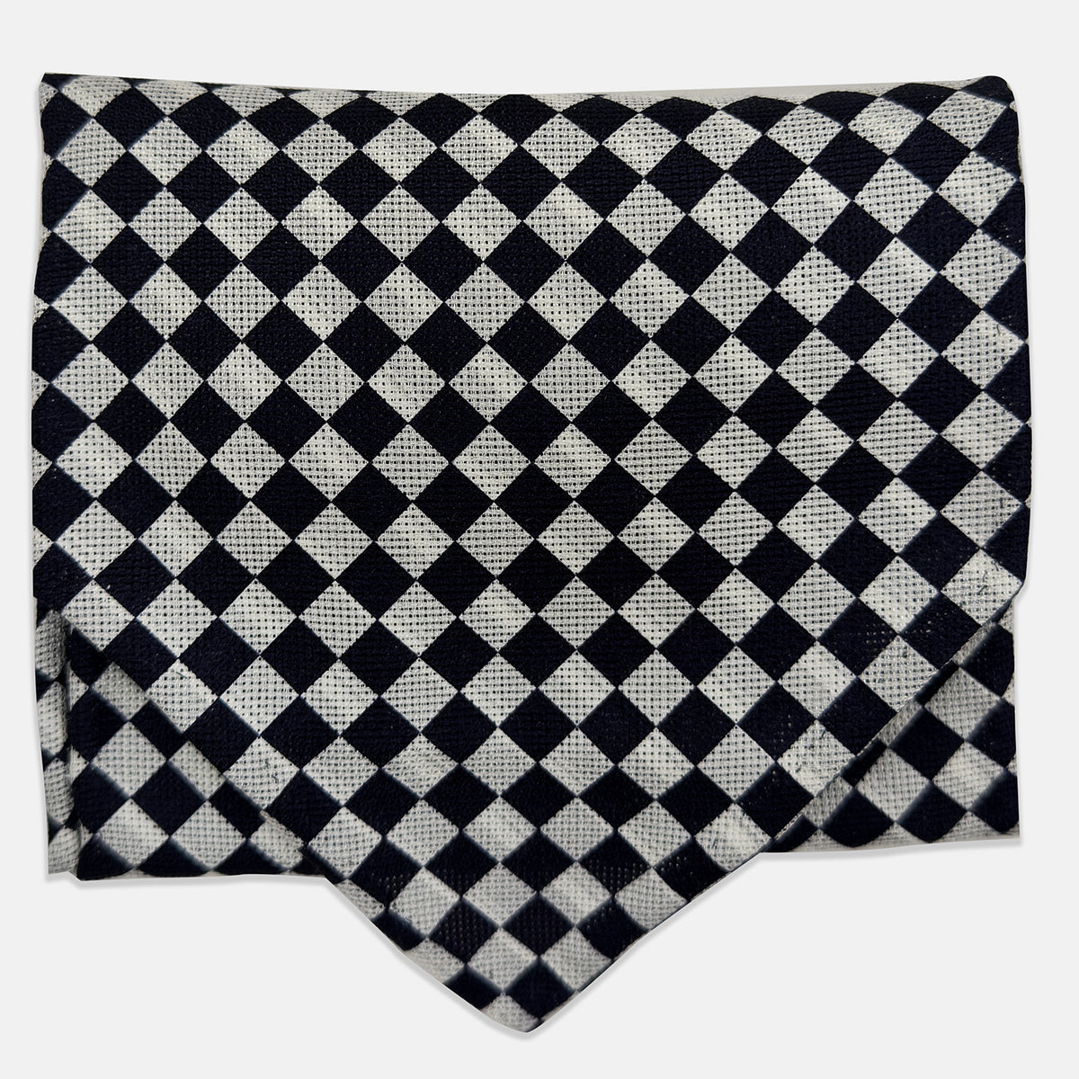 View 1 of product A folded Chequered Navy & White Silk Cravat by Turnbull & Asser UK, featuring a timeless diamond checkered pattern that channels classic British motoring elegance, displayed on a plain white background. Ideal as a double-sided silk accessory to elevate your ensemble for the Concours of Elegance 2026.