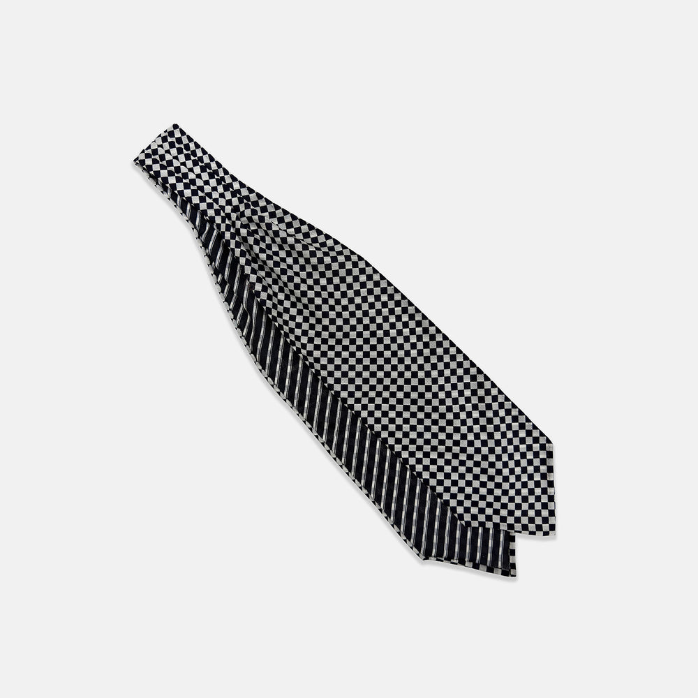 A Chequered Navy & White Cravat in Silk by Turnbull & Asser UK, featuring a checkered pattern on one side and diagonal stripes on the other, is laid flat on a white background.