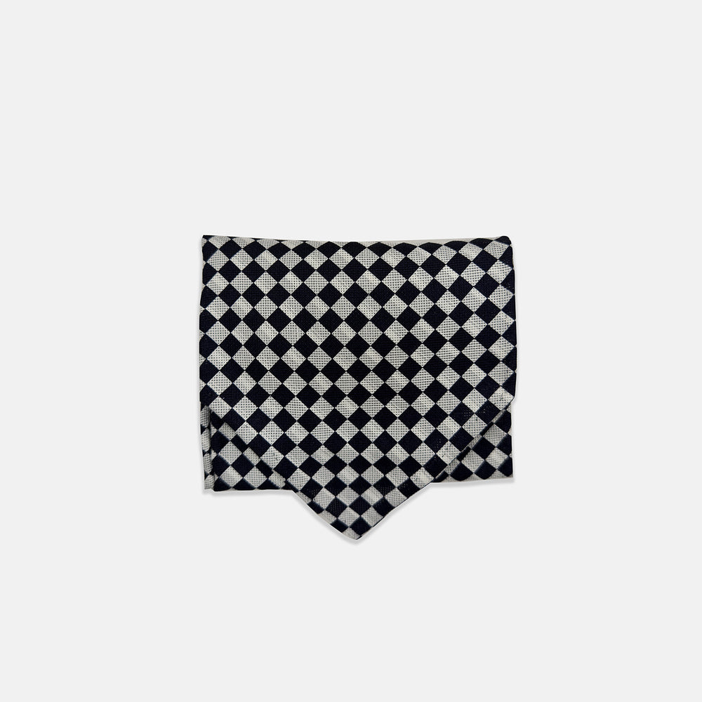 A Chequered Navy & White Cravat in Silk by Turnbull & Asser UK, featuring a checkered pattern on one side and diagonal stripes on the other, is laid flat on a white background.