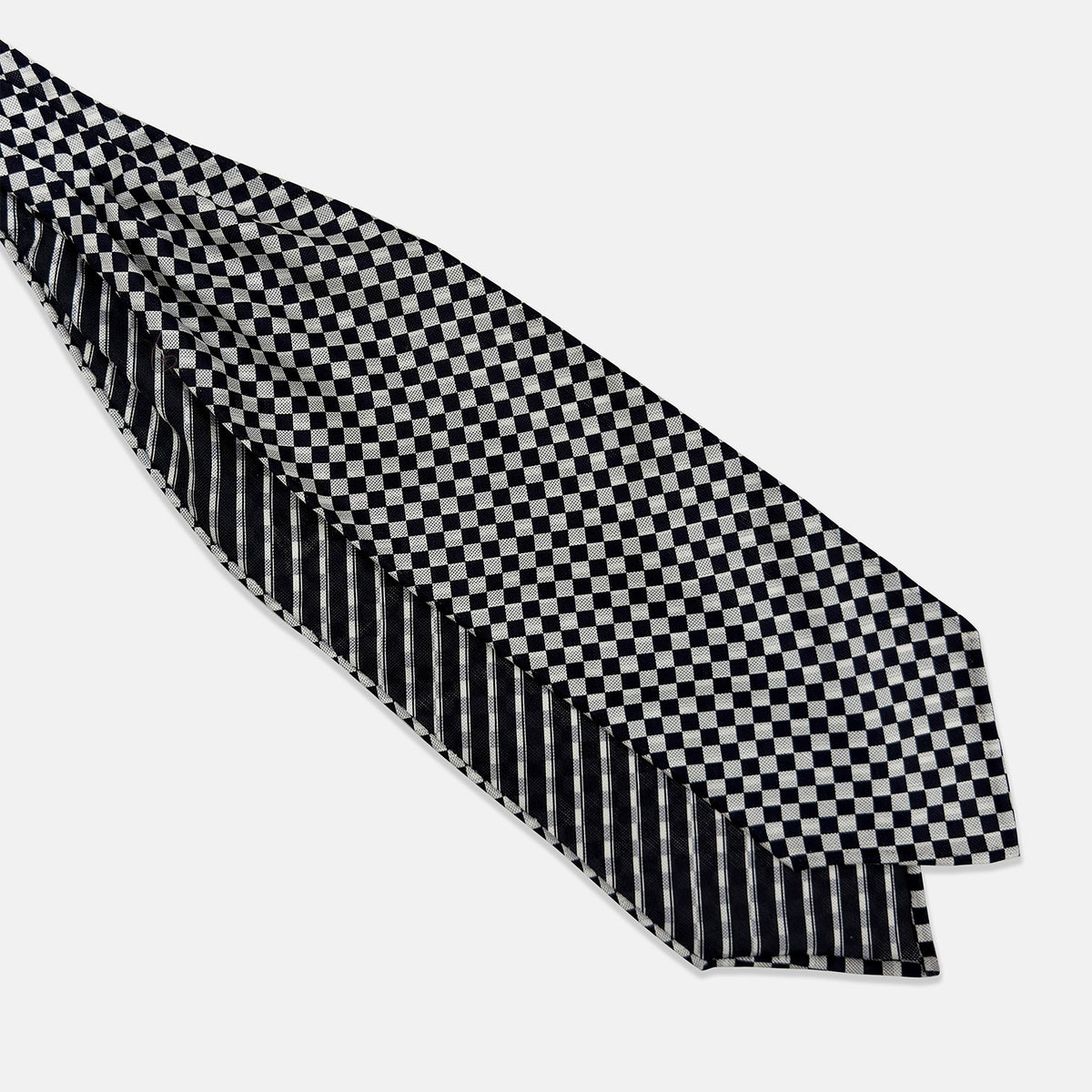 View 3 of product A folded Chequered Navy & White Silk Cravat by Turnbull & Asser UK, featuring a timeless diamond checkered pattern that channels classic British motoring elegance, displayed on a plain white background. Ideal as a double-sided silk accessory to elevate your ensemble for the Concours of Elegance 2026.