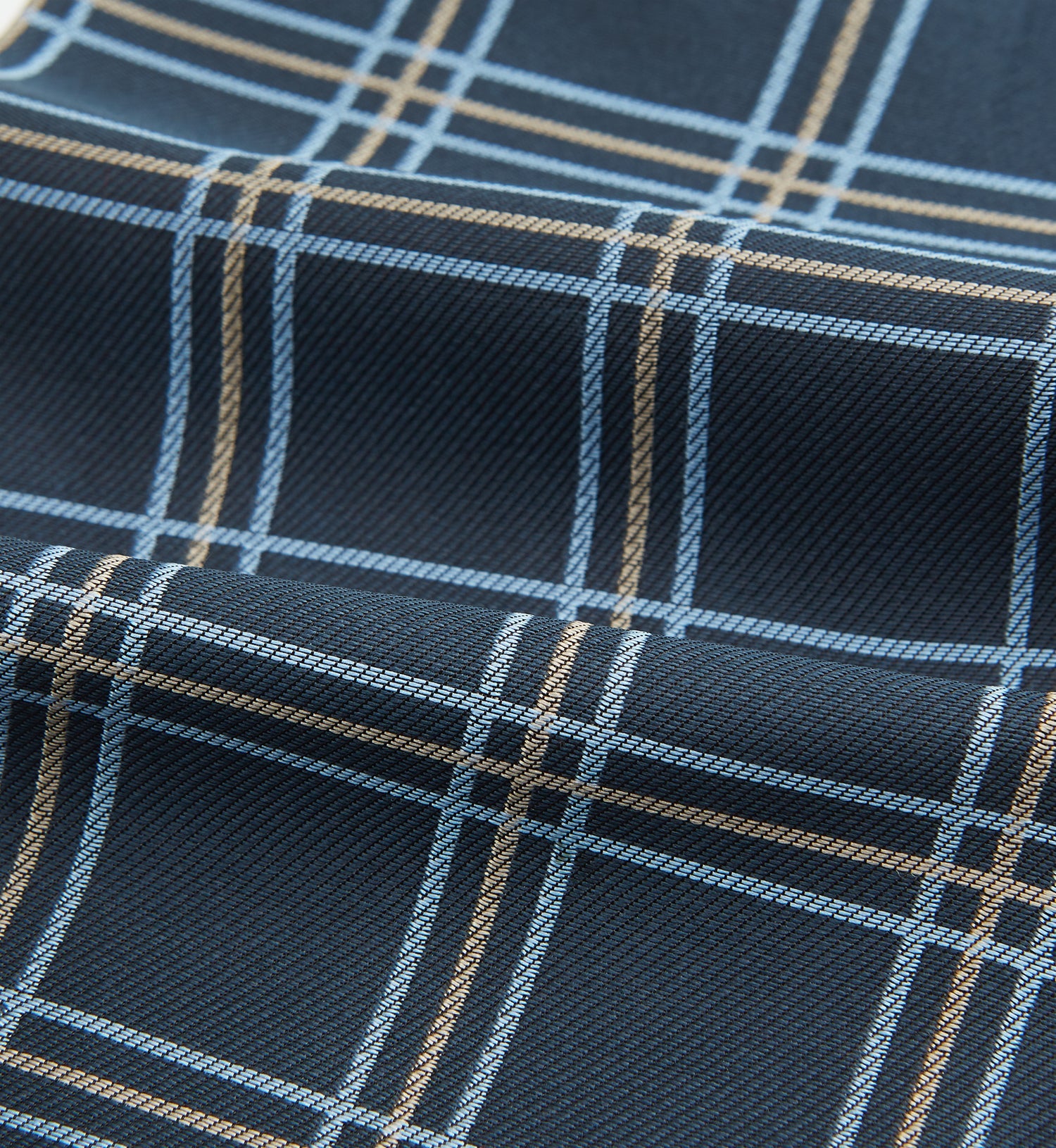 View 4 of product The Turnbull & Asser Navy Triple Check Silk Cravat features a classic navy, white, and light blue plaid design—perfect for adding elegance to any outfit. Shown neatly folded on a white background.