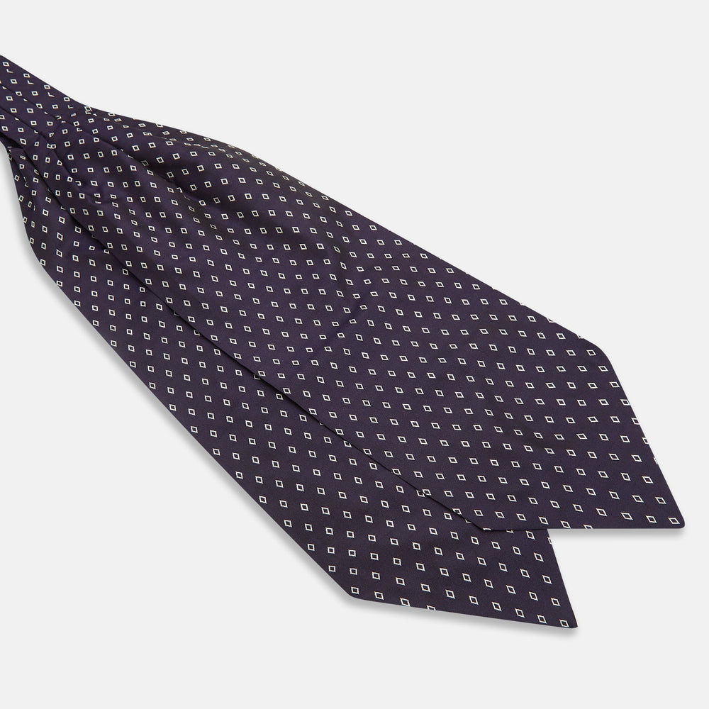 The Turnbull & Asser Blue Diamond Silk Cravat is a refined men's formal accessory, featuring a navy blue base with small white diamond patterns—perfectly complemented by a neatly folded, pointed-corner pocket square.