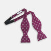 View 2 of product The Magenta Motif Silk Bow Tie by Turnbull & Asser features a textured magenta background with small, square blue, white, and gold geometric designs—an elegant choice for formal occasions.