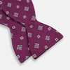 View 3 of product The Magenta Motif Silk Bow Tie by Turnbull & Asser features a textured magenta background with small, square blue, white, and gold geometric designs—an elegant choice for formal occasions.