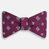 View 1 of product The Magenta Motif Silk Bow Tie by Turnbull & Asser features a textured magenta background with small, square blue, white, and gold geometric designs—an elegant choice for formal occasions.
