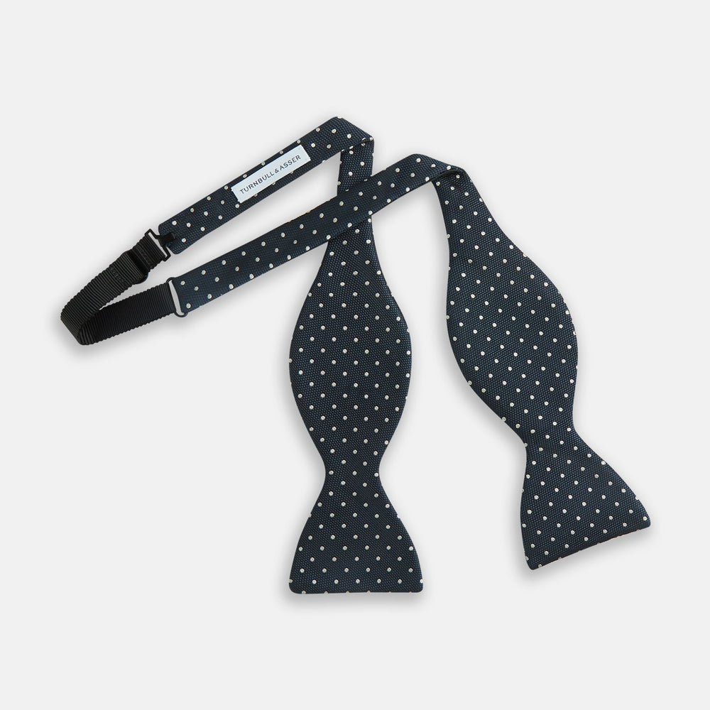 The Turnbull & Asser Navy Micro Dot Silk Bow Tie, shown on a white background, embodies British sophistication and classic formal style.