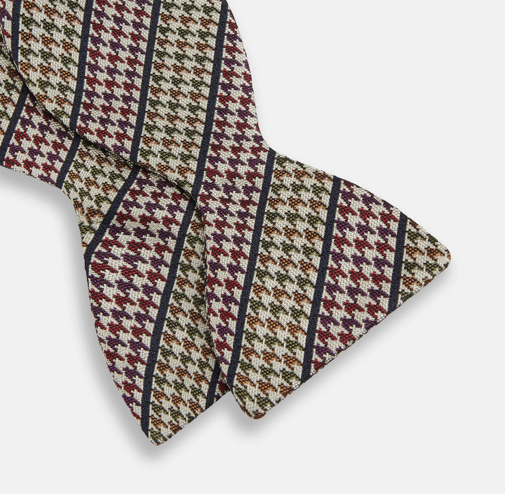 The Brown Puppytooth Stripe Silk Bow Tie by Turnbull & Asser features a houndstooth pattern in brown, beige, and burgundy with navy stripes—an elegant choice for formal occasions. Shown on a crisp white background.