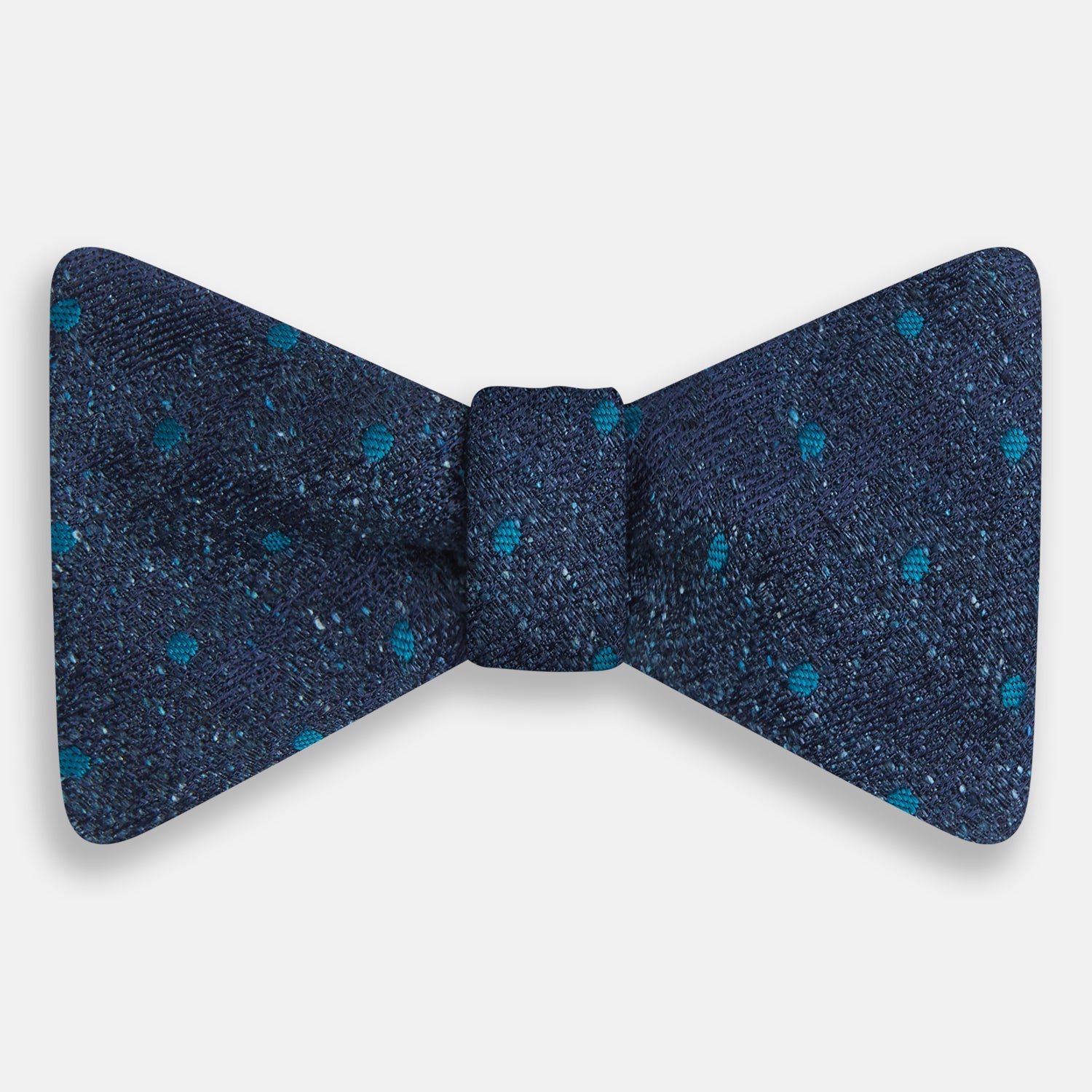 View 1 of product The Turnbull & Asser Teal Micro Dot Silk Bow Tie features textured navy blue silk with small teal dots, showcasing British elegance against a white background.