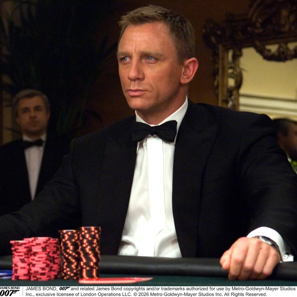The Casino Royale Shantung Silk Bow Tie by Turnbull & Asser, as seen on James Bond, features a classic shape in black silk and is set against a plain white background—a timeless gentleman’s accessory.