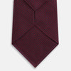 View 3 of product A close-up of the Turnbull & Asser UK Seven-Fold Navy and Red Silk Tie, featuring a small textured check pattern reminiscent of houndstooth, displayed on a plain white background.