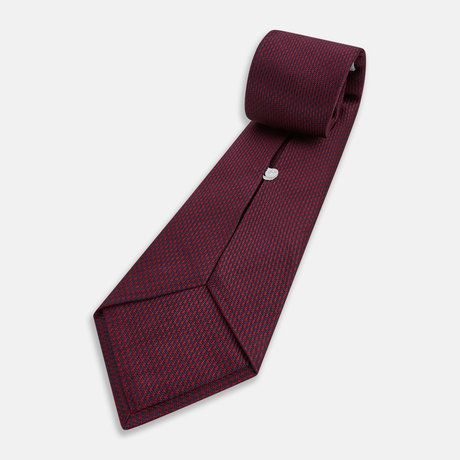 View 5 of product A close-up of the Turnbull & Asser UK Seven-Fold Navy and Red Silk Tie, featuring a small textured check pattern reminiscent of houndstooth, displayed on a plain white background.