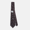 View 4 of product The Tomorrow Never Dies Seven-Fold Silk Tie by Turnbull & Asser UK features a geometric pattern of navy and brown squares with light blue diamond accents, rolled up and displayed on a plain white background.