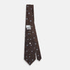 View 4 of product The Turnbull & Asser UK Tomorrow Never Dies Seven-Fold Silk Tie, as seen on James Bond, features a navy blue and brown geometric diamond pattern with silver squares at the center, set on a light background.