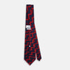 View 4 of product The Turnbull & Asser UK Seven-Fold Silk Red and Navy Geometric Tie is displayed rolled with its tip forward, showcasing its bold navy and red geometric pattern against a plain white background.