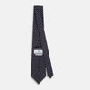View 4 of product The Turnbull & Asser Navy and Red Circle Foulard Silk Tie, featuring a repeating red and white circular motif, is neatly rolled to display classic British craftsmanship.