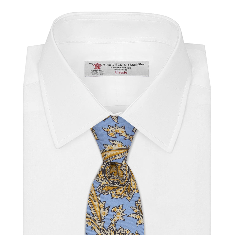 The Turnbull & Asser GGT92000 3062 06 OS is a rolled-up necktie with an intricate blue and yellow paisley pattern on a light blue background—a stylish accessory for any wardrobe.