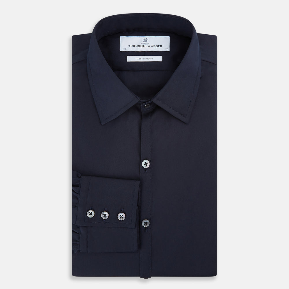 The Navy Westminster Shirt by Turnbull & Asser is a classic long-sleeve, button-up shirt with a pointed collar and buttoned cuffs, exemplifying British craftsmanship, shown against a plain white background.