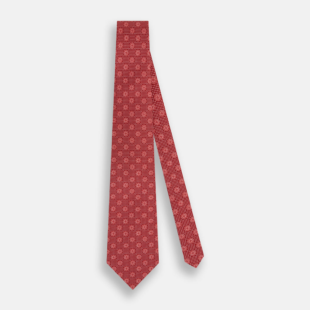 The Turnbull & Asser Red Medallion Silk Tie features a repeating white geometric medallion motif on vibrant red silk, shown against a plain white background.