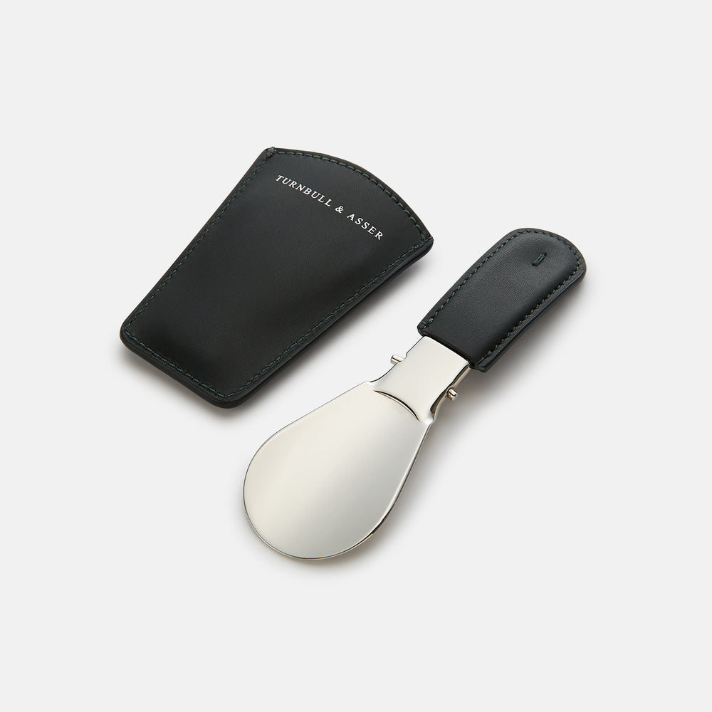The Turnbull & Asser Navy Travel Shoe Horn features a wide, smooth silver blade and a navy leather-wrapped handle, shown against a plain white background.