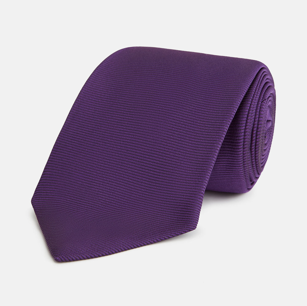 The HORIZONTAL TWILL PLUM TIE by Turnbull & Asser features a solid purple hue and smooth, subtly textured fabric—a versatile accessory to elevate any wardrobe, shown elegantly against a white background.