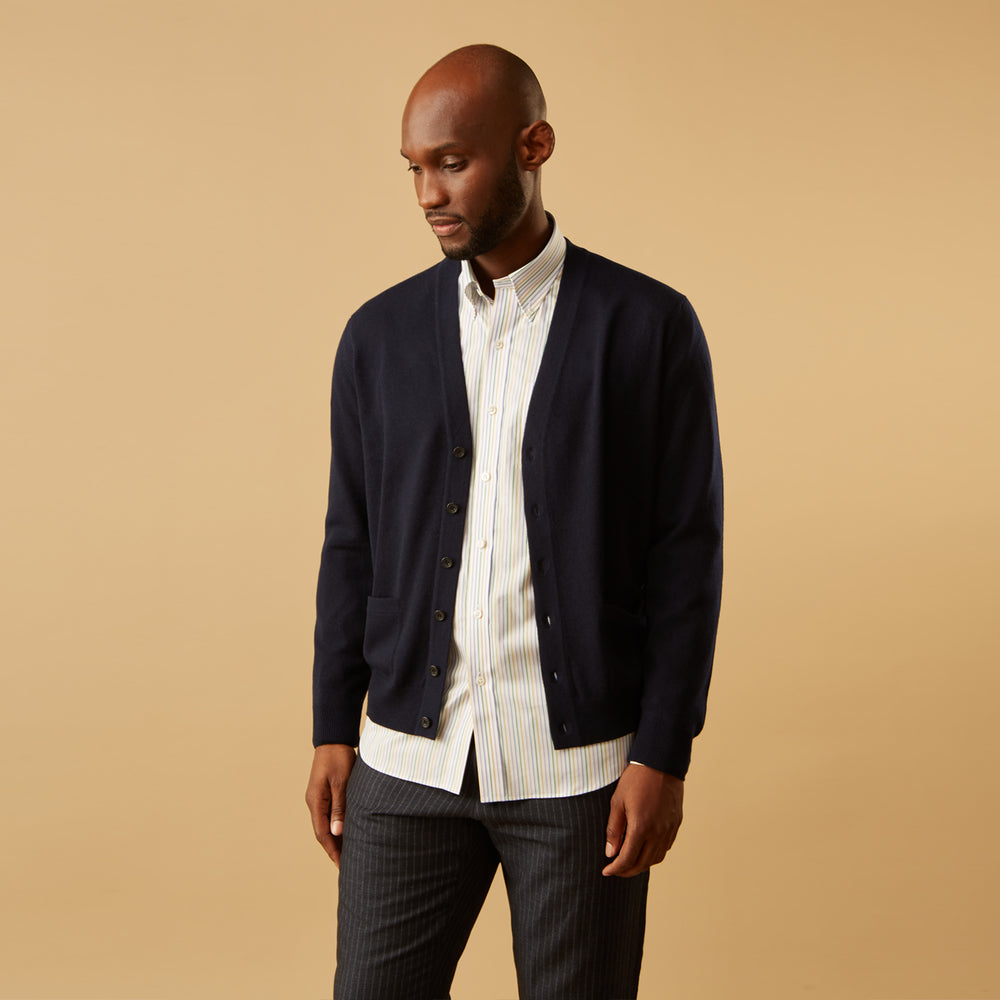 A man wears the Turnbull & Asser Yellow Multi Blazer Stripe Weekend Fit Suffolk Shirt, standing against a beige background with his hands relaxed—a casual look perfect for weekends.