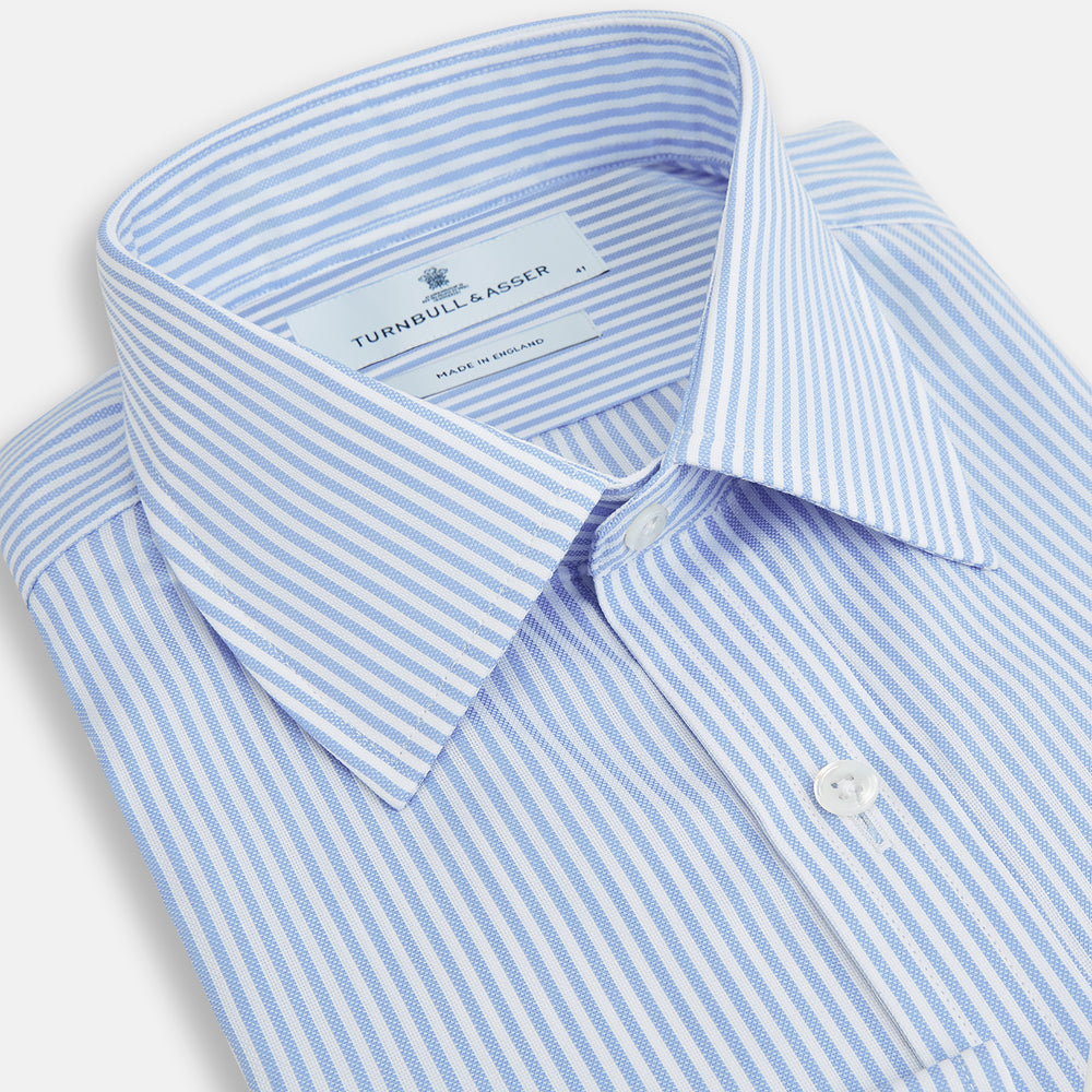 The Turnbull & Asser Blue Bengal Stripe Mayfair Shirt features light blue and white vertical stripes, a classic T&A collar, white buttons, and buttoned cuffs. Laid flat on a white background.