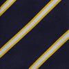View 3 of product The Yellow and White Blazer Silk Tie by Turnbull & Asser, featuring diagonal white and yellow stripes on navy blue, is shown rolled up against a light gray background.