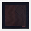 View 3 of product The Navy and Orange Stripe Silk Pocket Square by Turnbull & Asser is handmade in England from silk, featuring thin orange geometric stripes on navy and "Turnbull & Asser Hand Printed in England" printed in the corner.