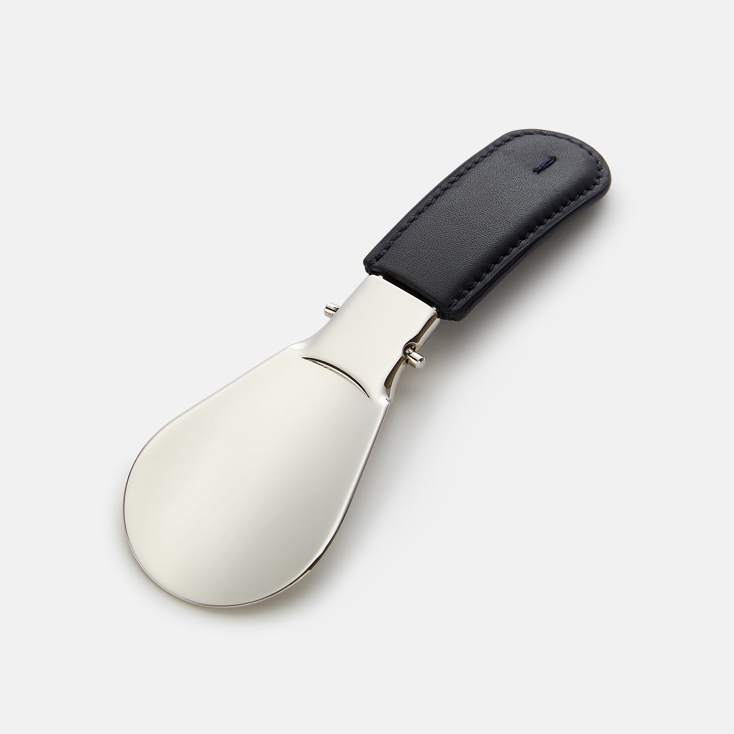 View 1 of product The Turnbull & Asser Navy Travel Shoe Horn features a wide, smooth silver blade and a navy leather-wrapped handle, shown against a plain white background.