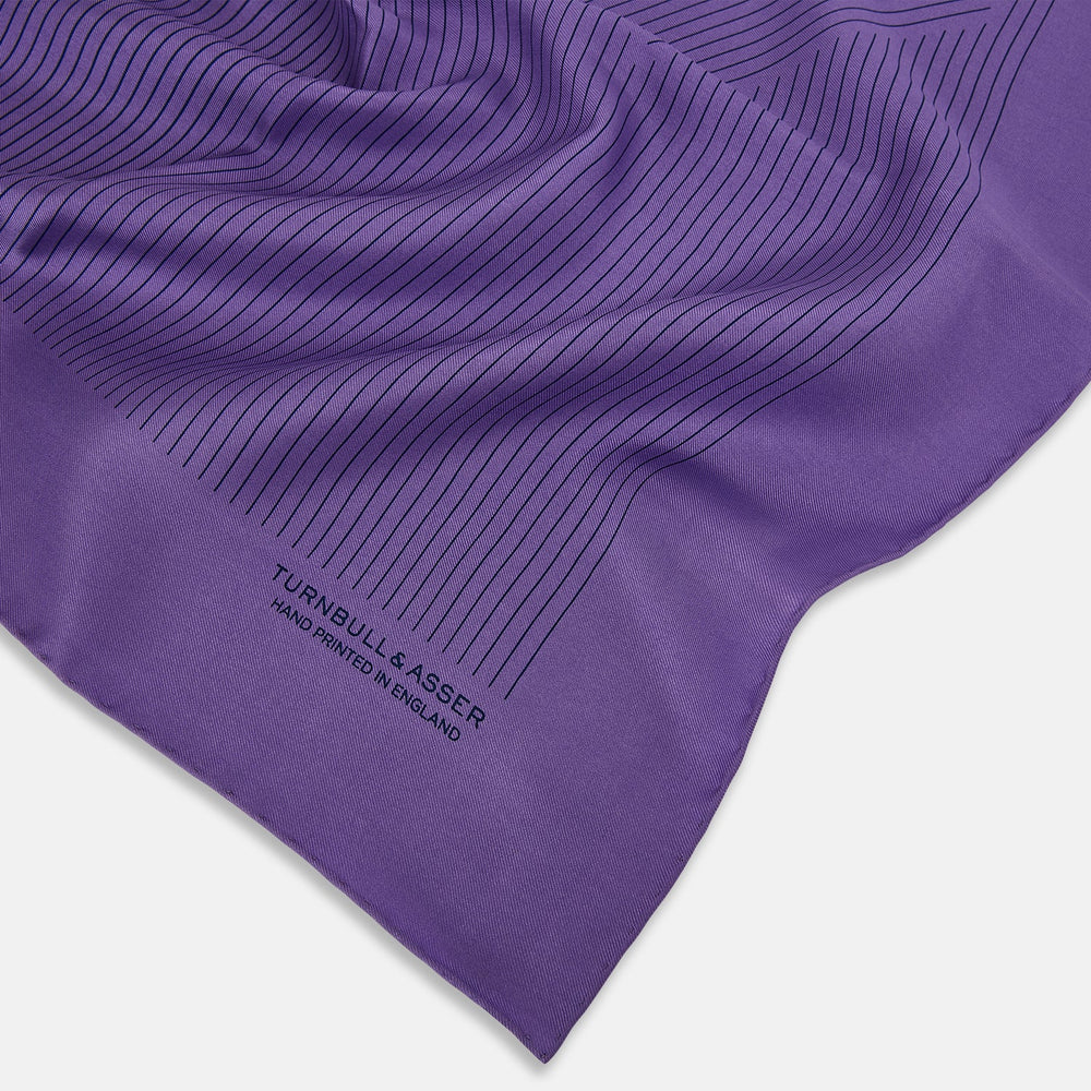 The Purple Stripe Silk Pocket Square by Turnbull & Asser features thin black lines on purple silk—a sophisticated blazer accessory hand printed in England, showcasing classic British craftsmanship.