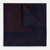 View 1 of product The Turnbull & Asser Navy and Red Dot Silk Pocket Square features a dark navy blue base with small red polka dots on the border and inner pattern, all handmade and neatly folded.