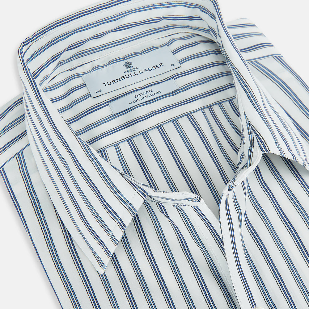 The SAPPHIRE BLUE MULTI TRACK STRIPE WINDSOR SHIRT by Turnbull & Asser features long sleeves, button-up front, classic collar, blue and white vertical stripes, buttoned cuffs, and showcases British craftsmanship on a white background.