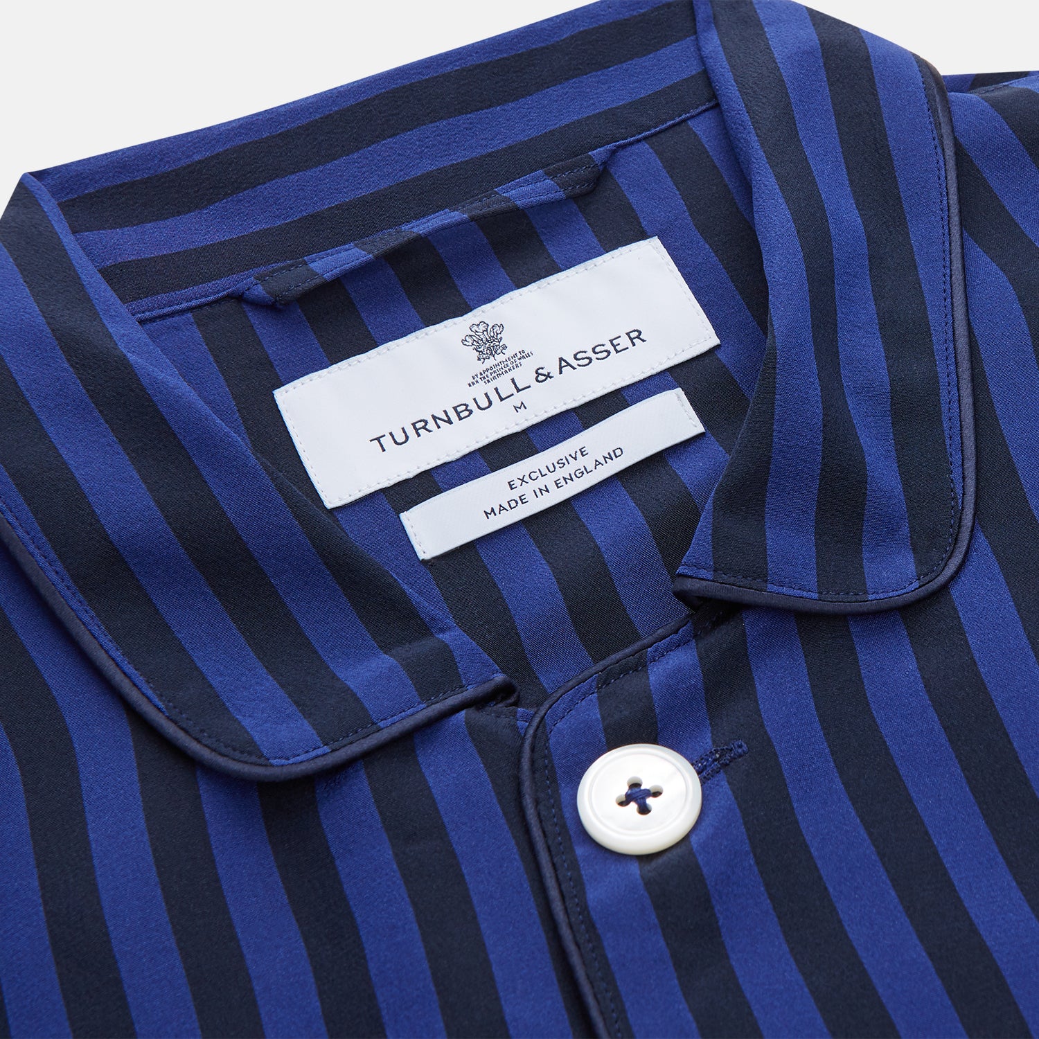View 4 of product The Turnbull & Asser Blue and Navy Candy Stripe Silk Hyde Pyjamas Set features a long-sleeve button-up top with a chest pocket and elastic-waist pants, shown on a plain white background.