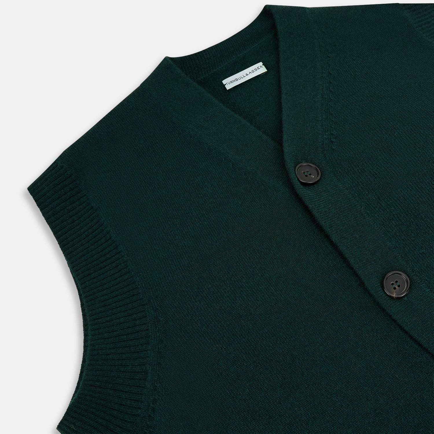 View 2 of product The Forest Green Cashmere Sleeveless Cardigan by Turnbull & Asser features a V-neck, button-down front, ribbed hem and armholes, and two front pockets—an elegant menswear staple shown on a plain white background.
