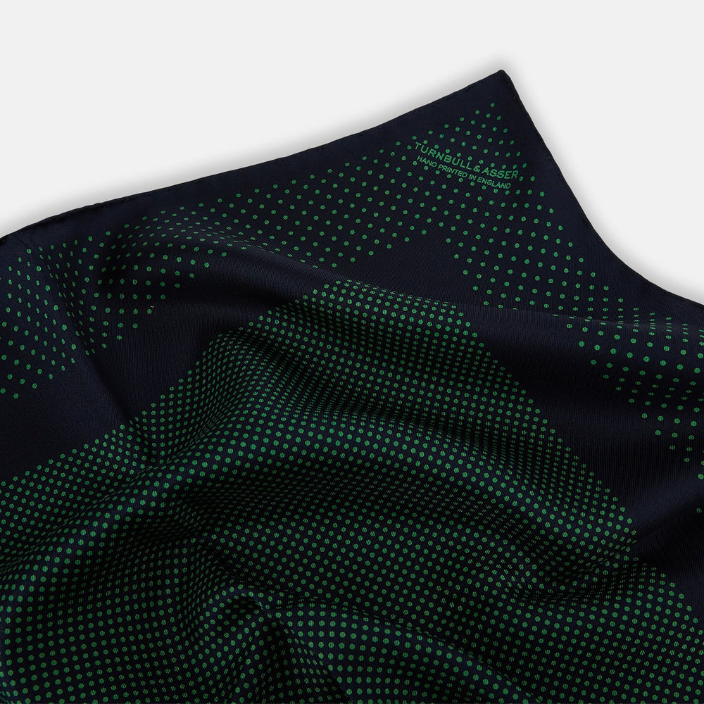 The Turnbull & Asser Navy and Green Dot Silk Pocket Square features dense green polka dots on navy silk, a solid navy border, and a band of spaced green dots—expertly handmade with precise finishing for an elegant look.