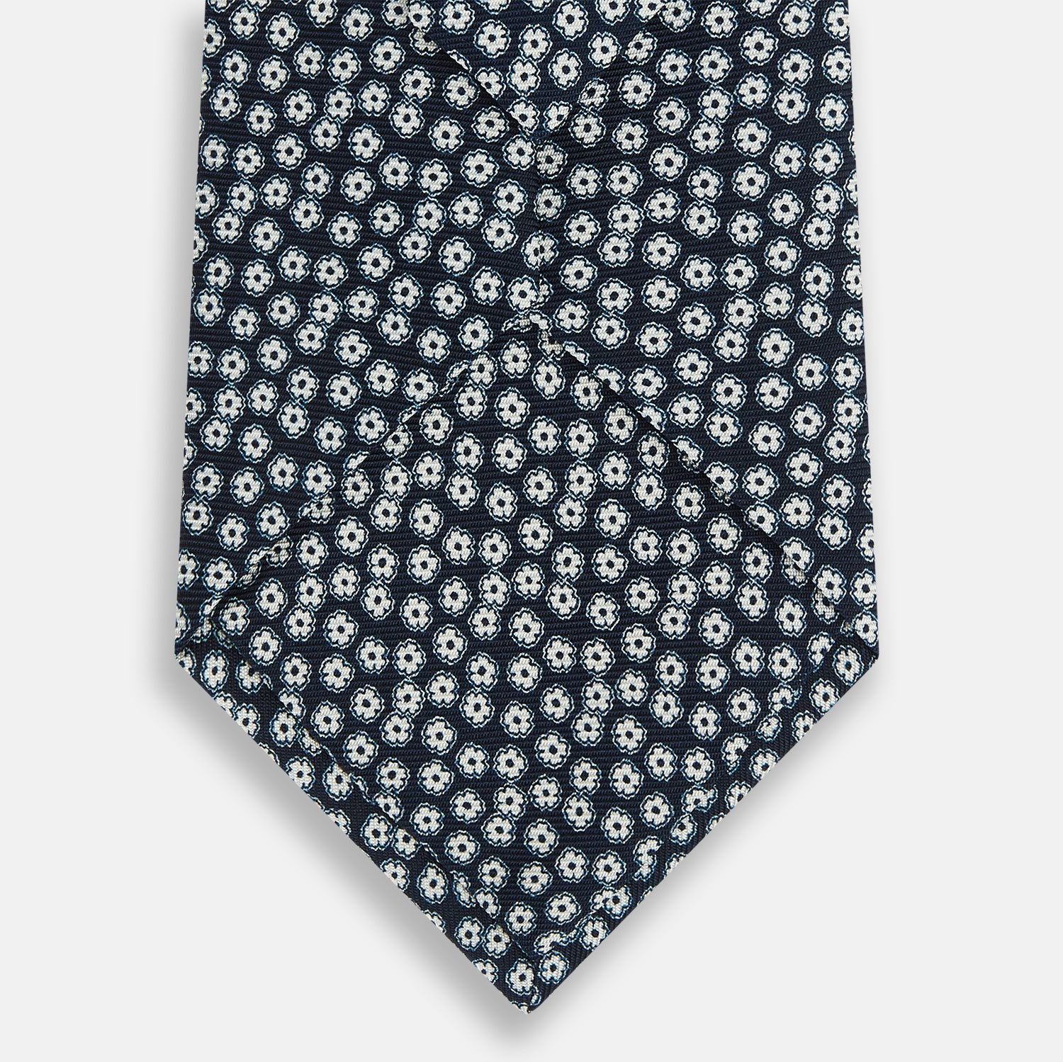 View 3 of product The Turnbull & Asser Navy Flower Patterned Printed Silk Tie features a repeating design of small white and light blue floral motifs on navy silk.